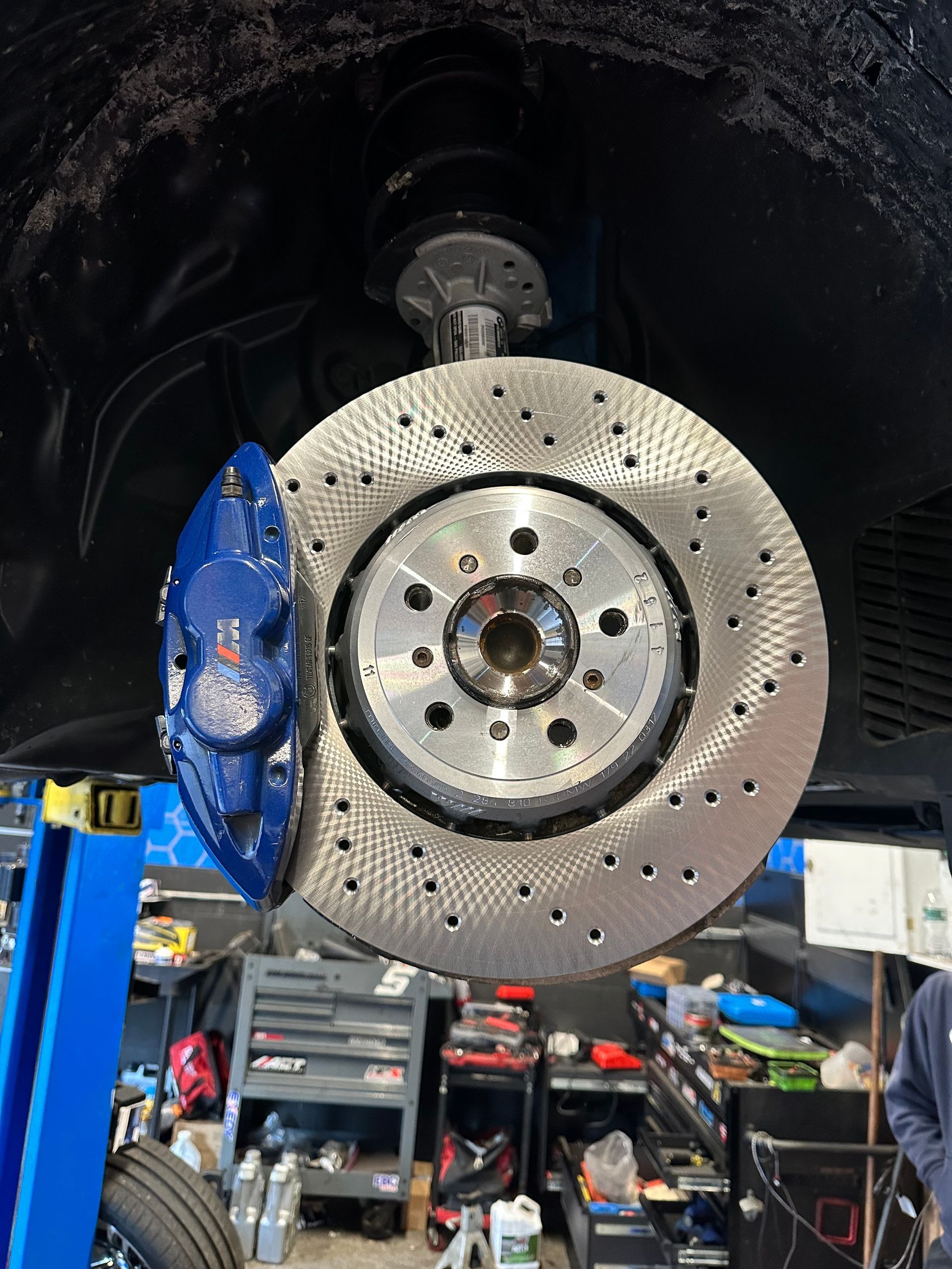 A close up of a brake disc on a car in a garage.