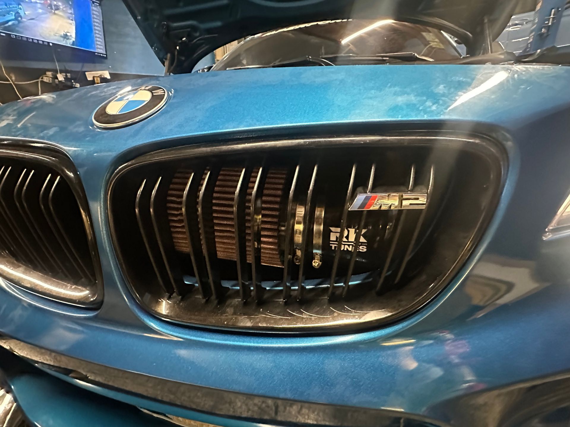 A close up of a blue bmw with the hood open.