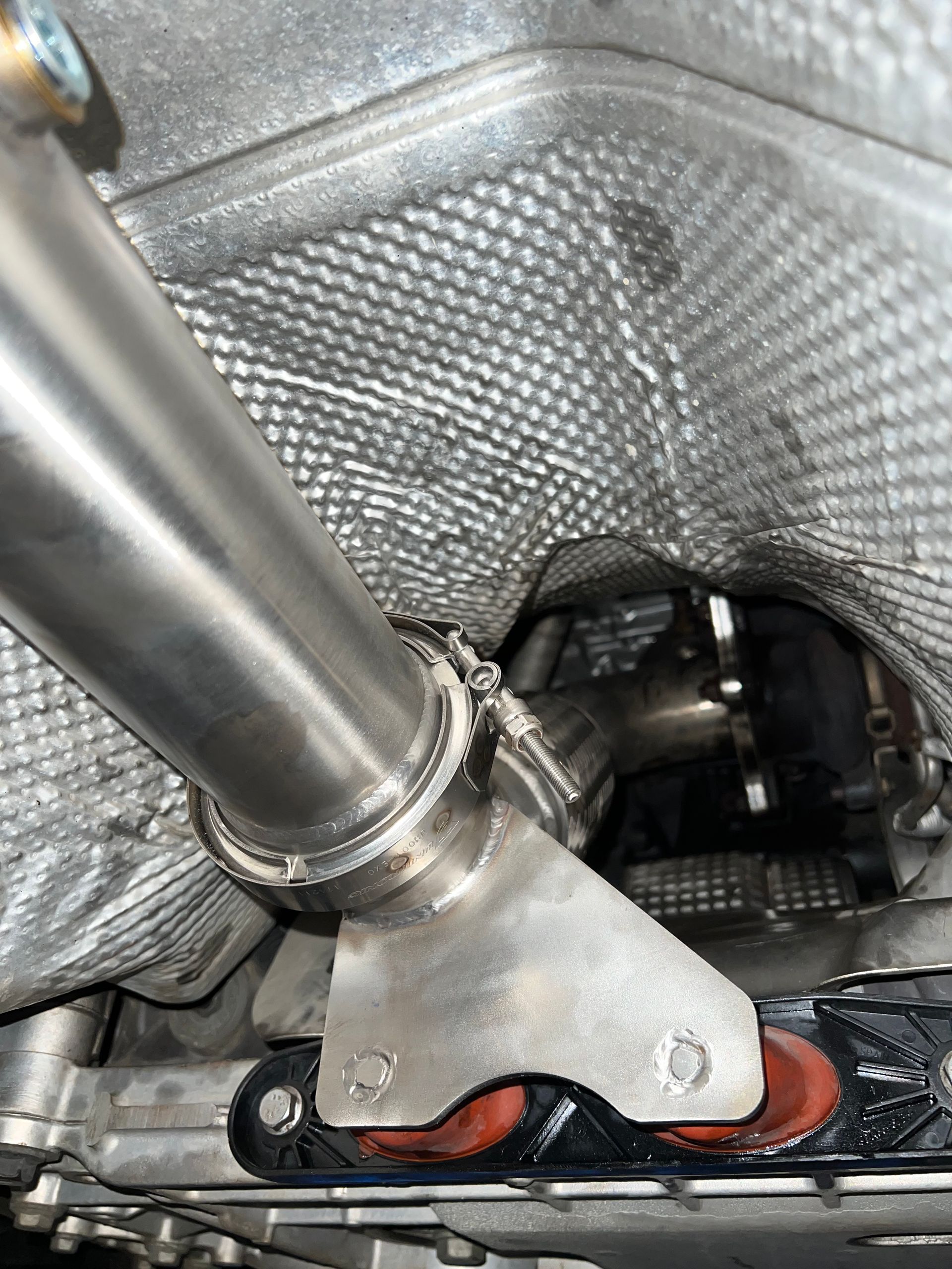 A close up of a stainless steel pipe under a car.