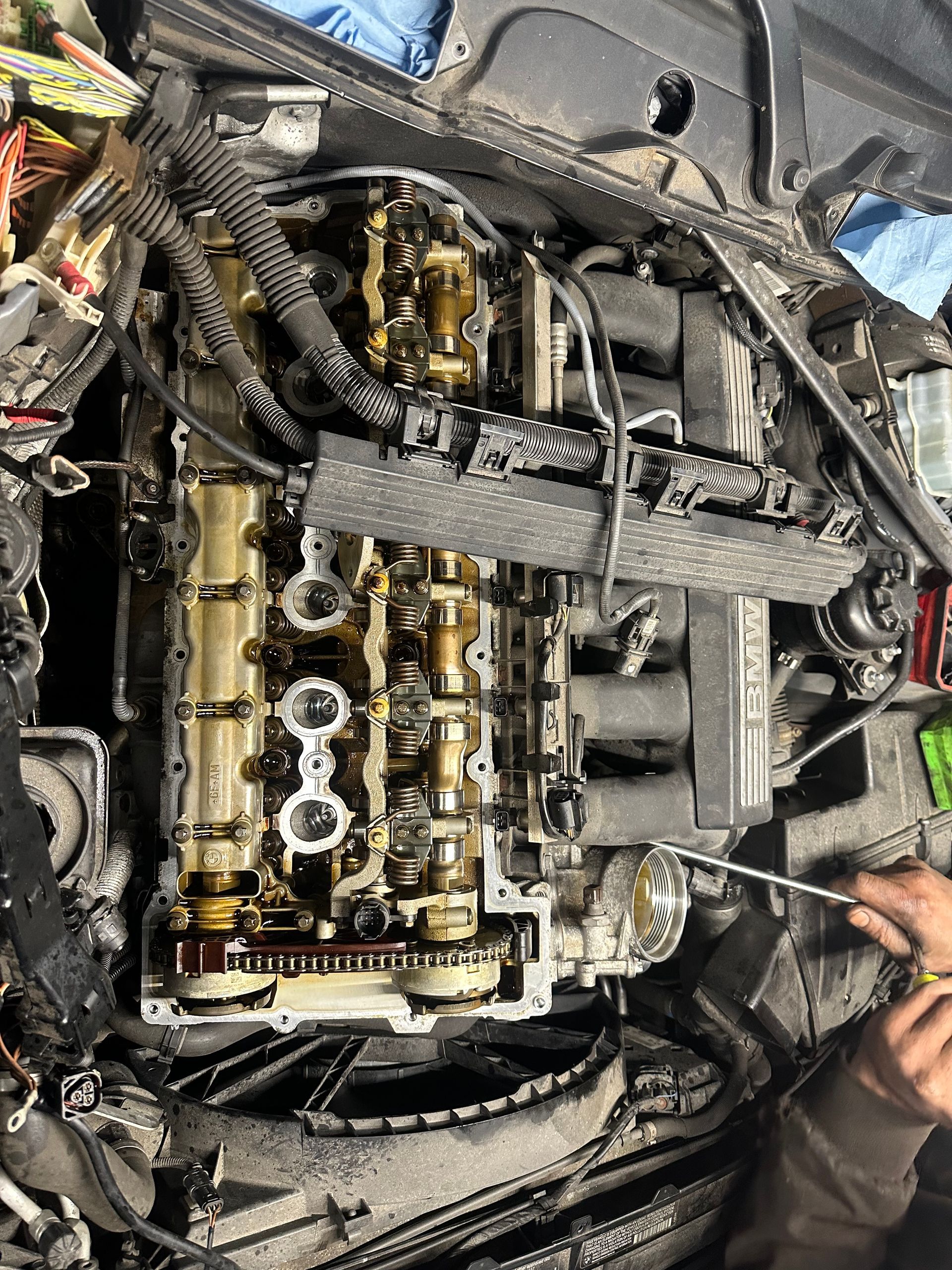 A person is working on a car engine with a screwdriver.