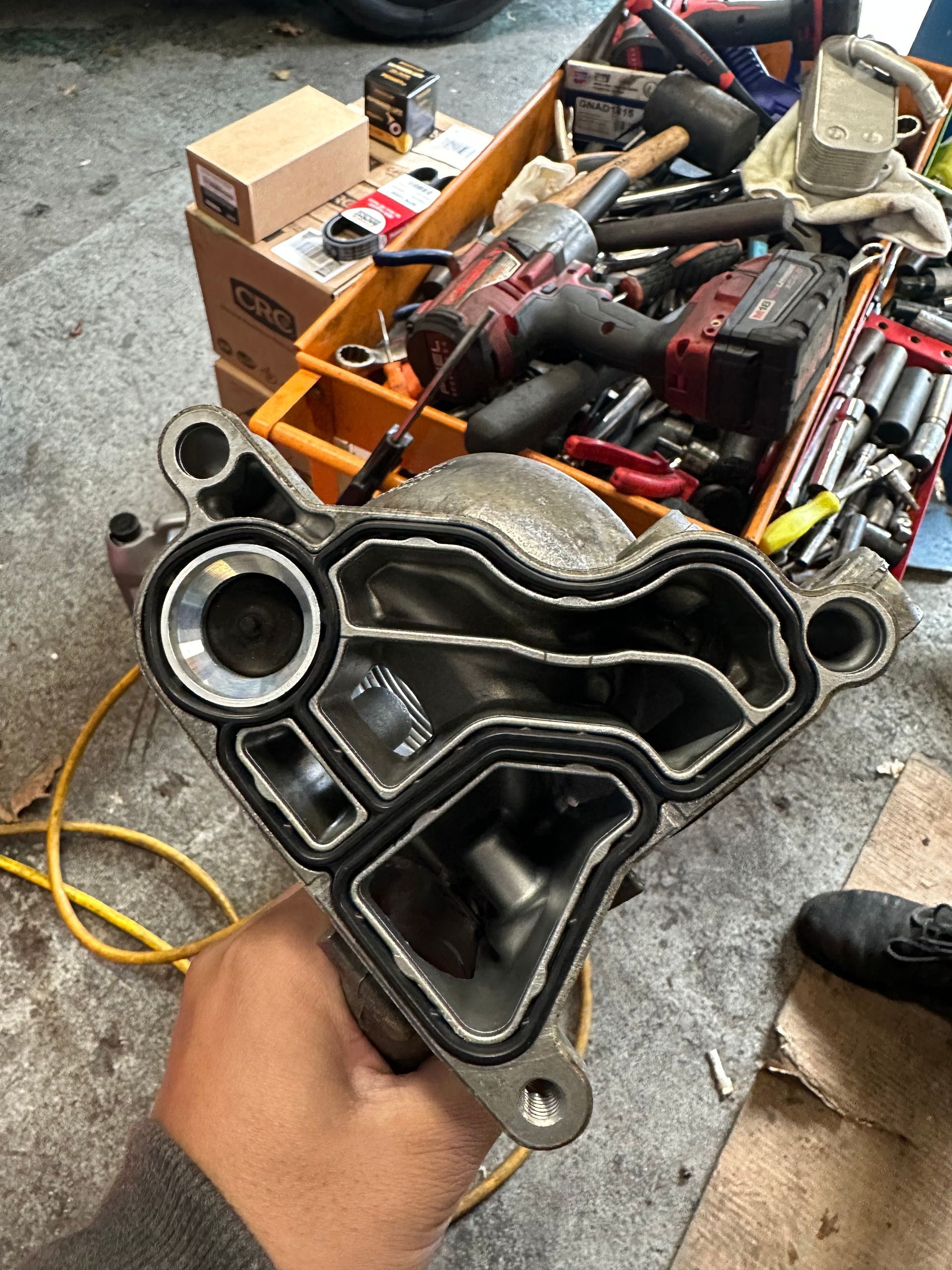 A person is holding a piece of metal in their hand in a garage.