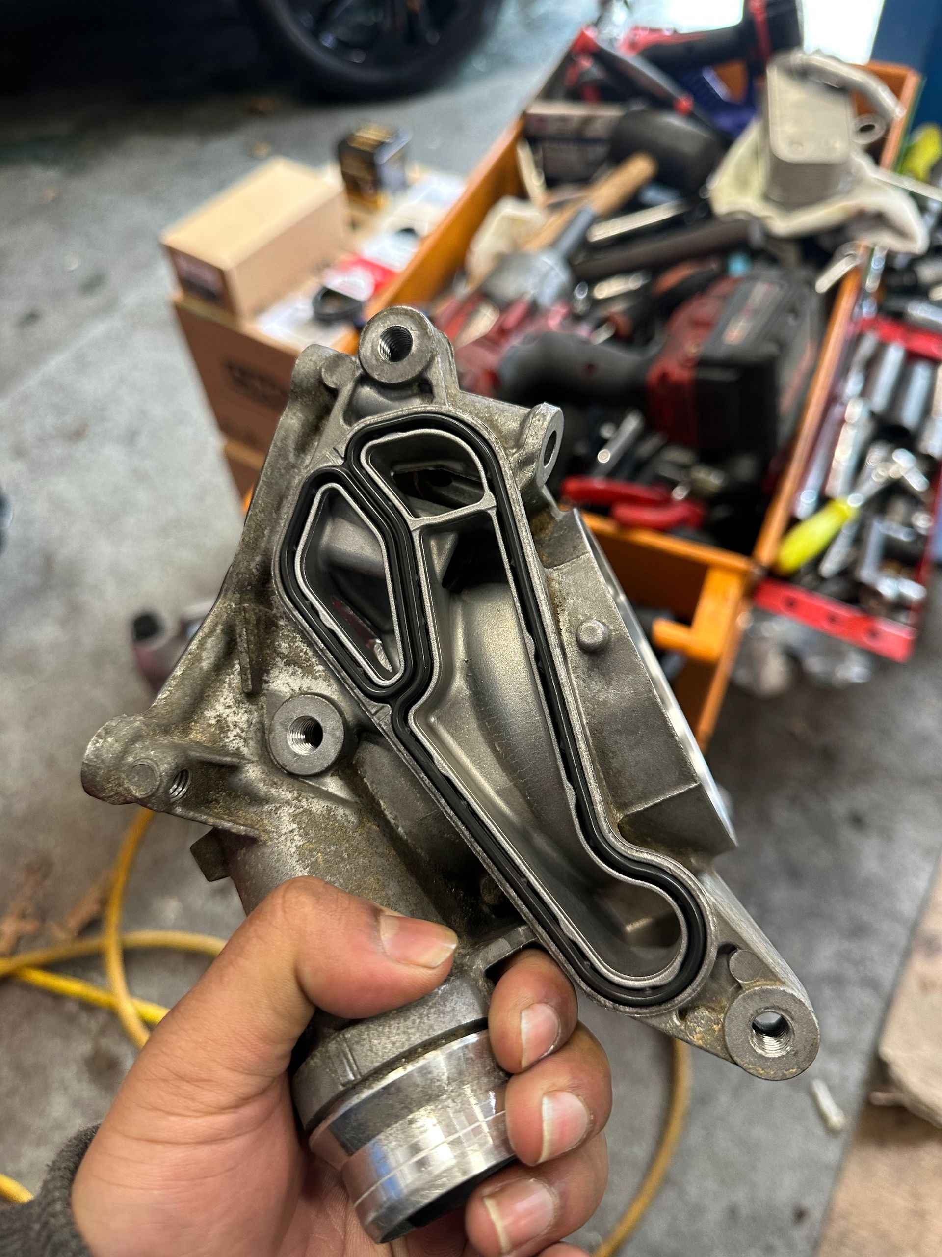 A person is holding a piece of metal in their hand in a garage.