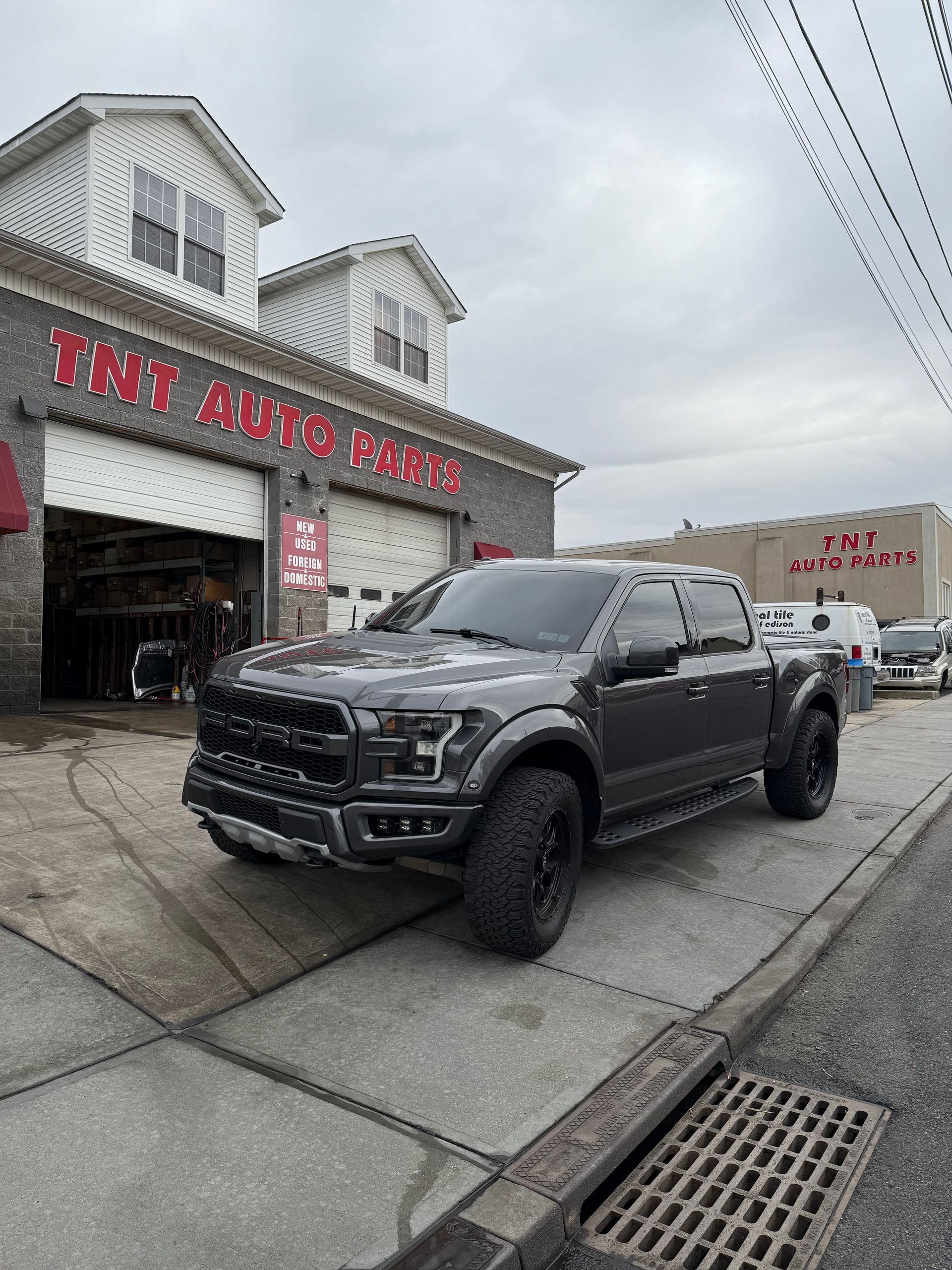 A ford raptor is parked in front of a car dealership.