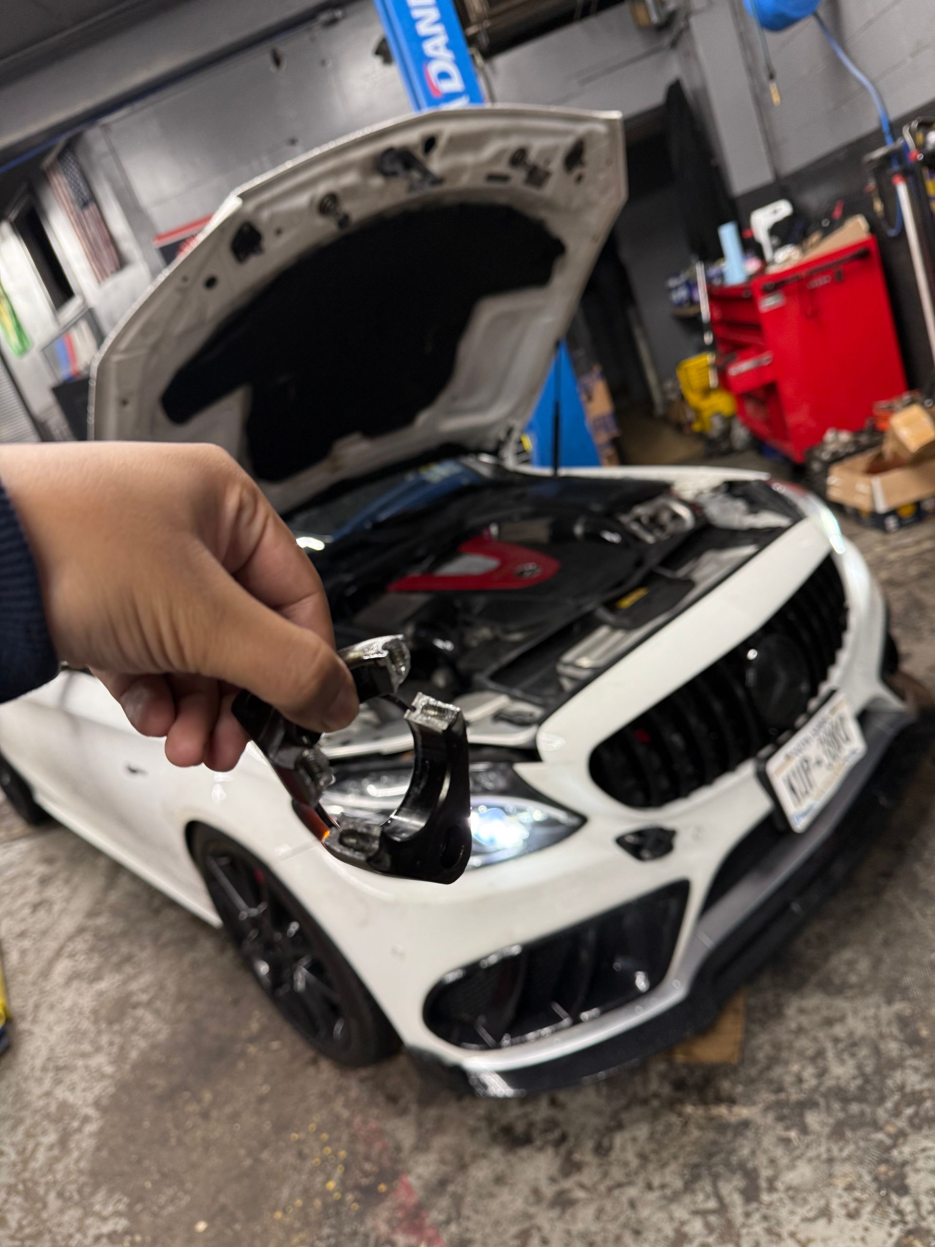 A person is opening the hood of a white car