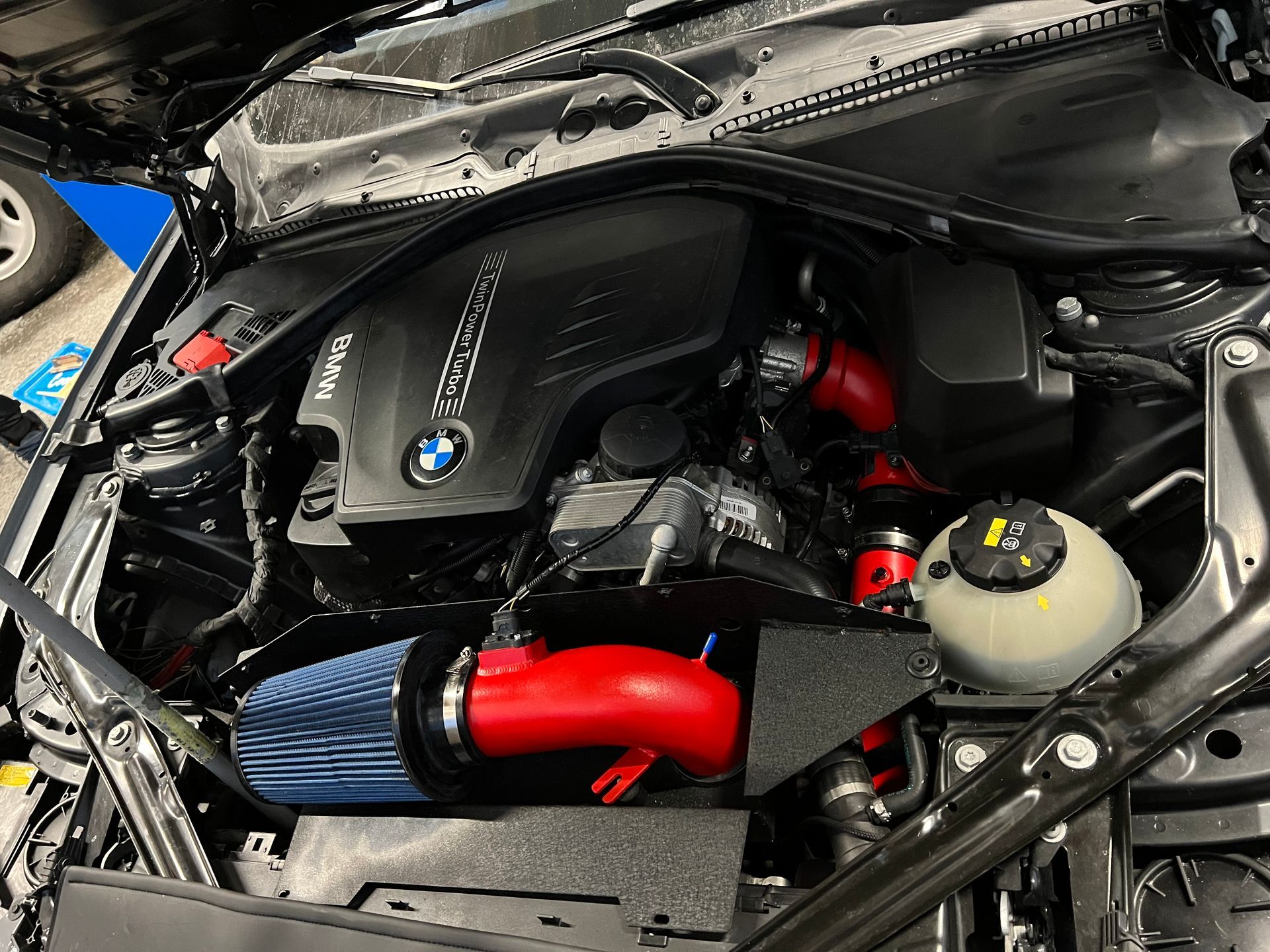 A close up of the engine of a car with a red pipe coming out of it.