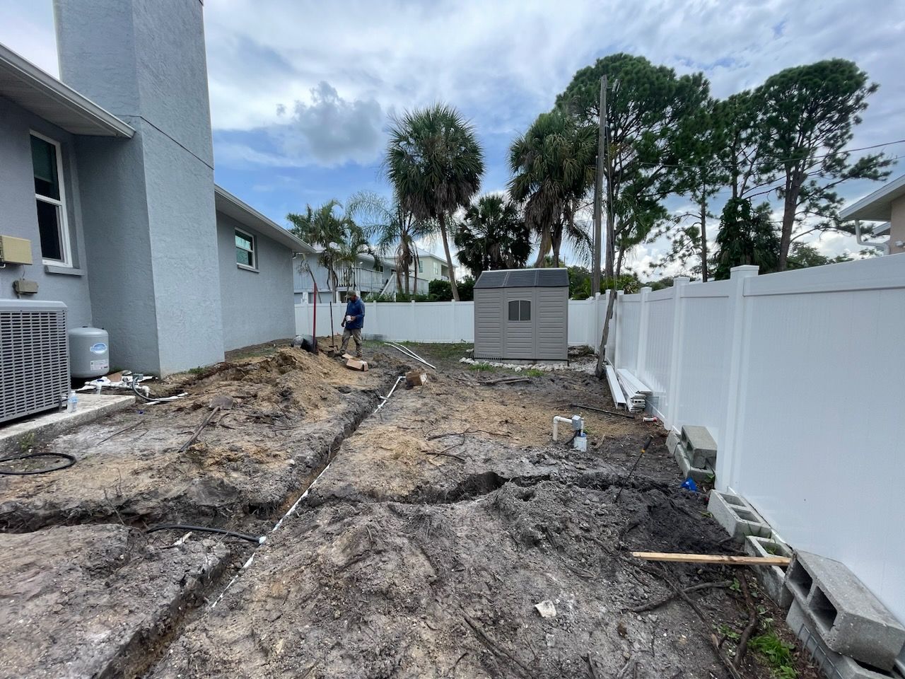 A man is digging in the dirt in front of a house.