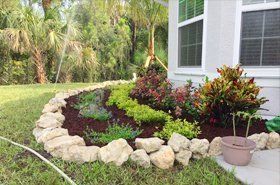 A garden with rocks and plants in front of a house.