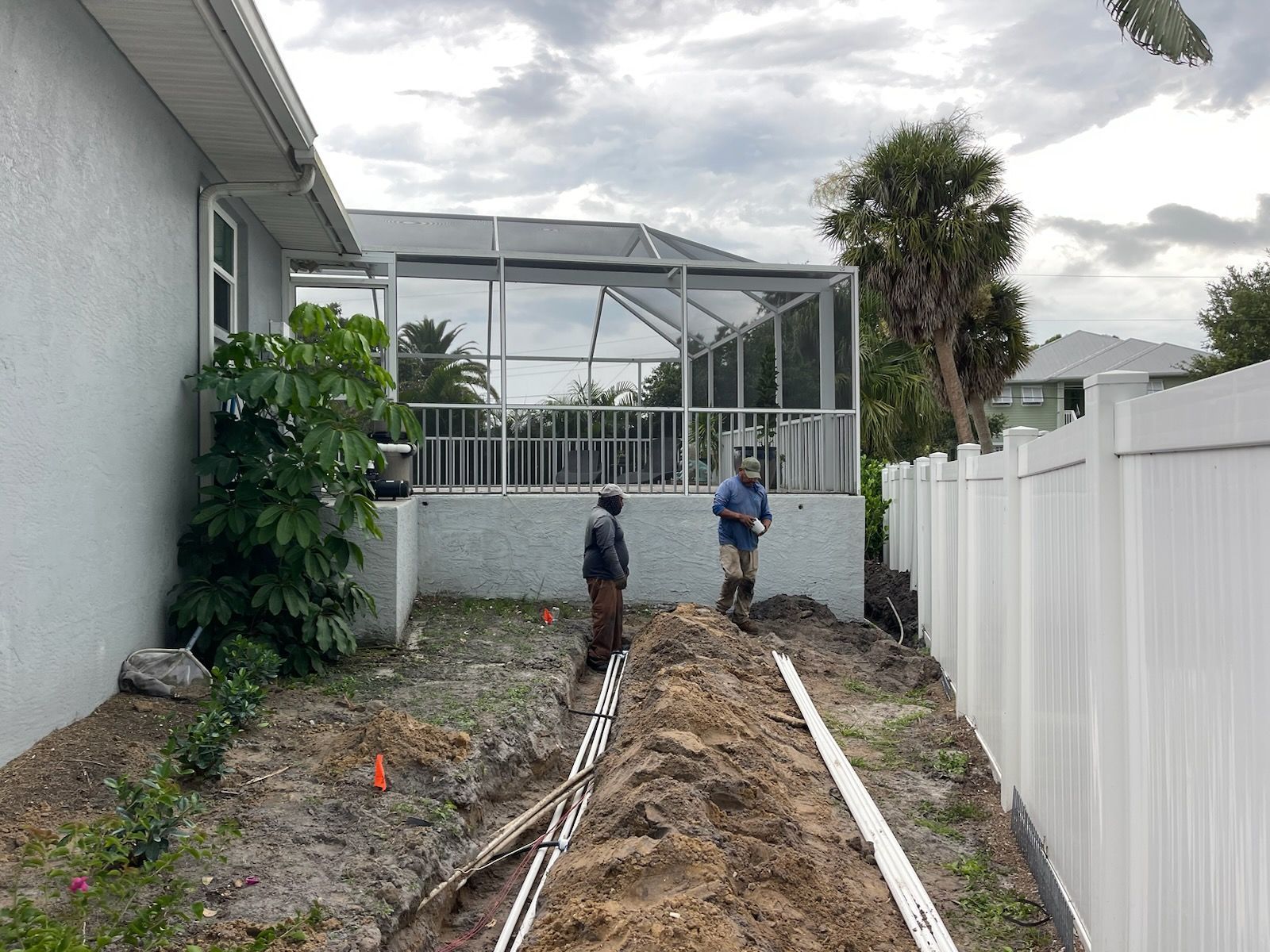 A couple of men are standing in the dirt in front of a house.