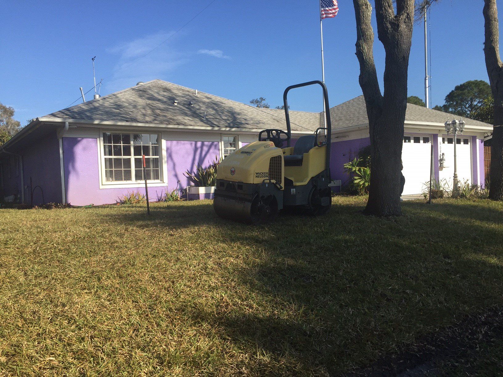 A yellow roller is parked in front of a purple house