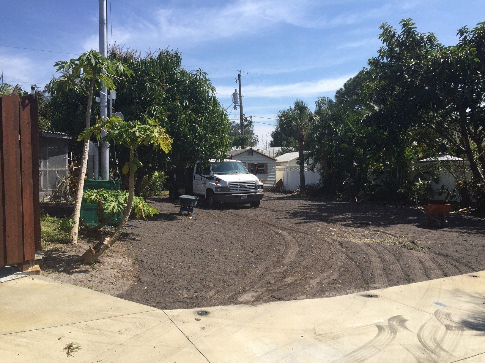 A white truck is parked in the middle of a dirt road