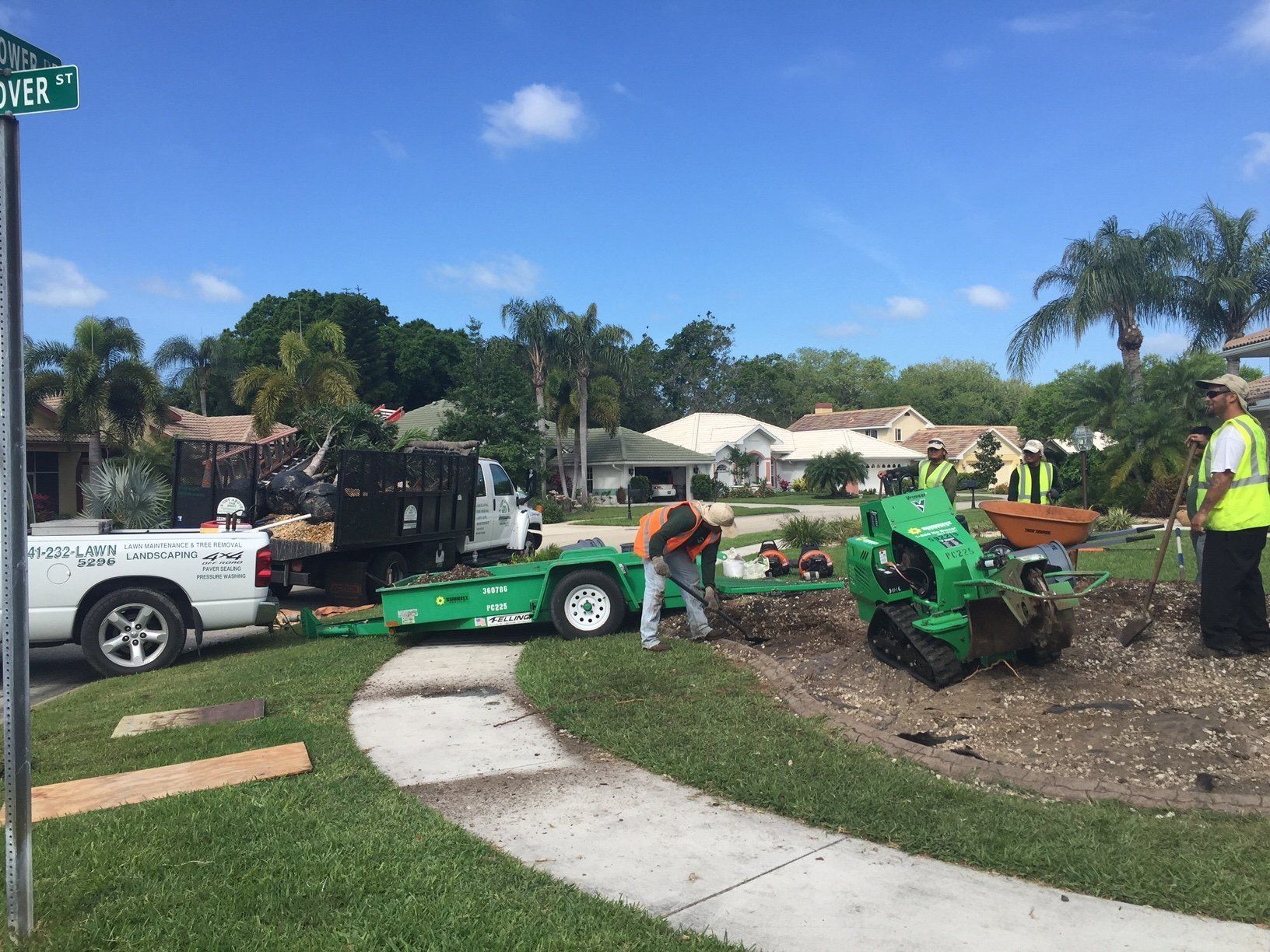 A group of men are working on a stump grinder in a yard.