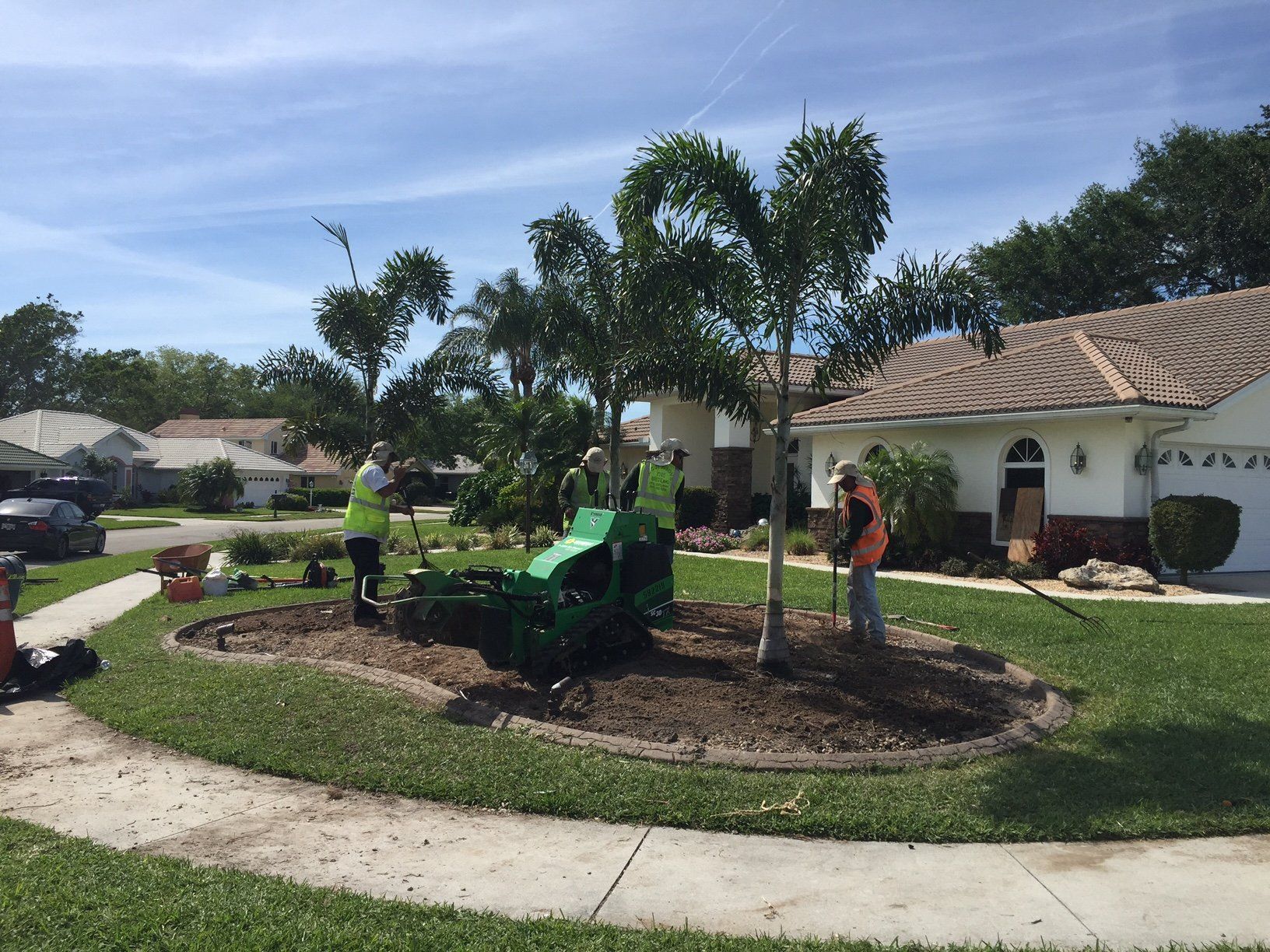 A group of people are working on a lawn in front of a house.