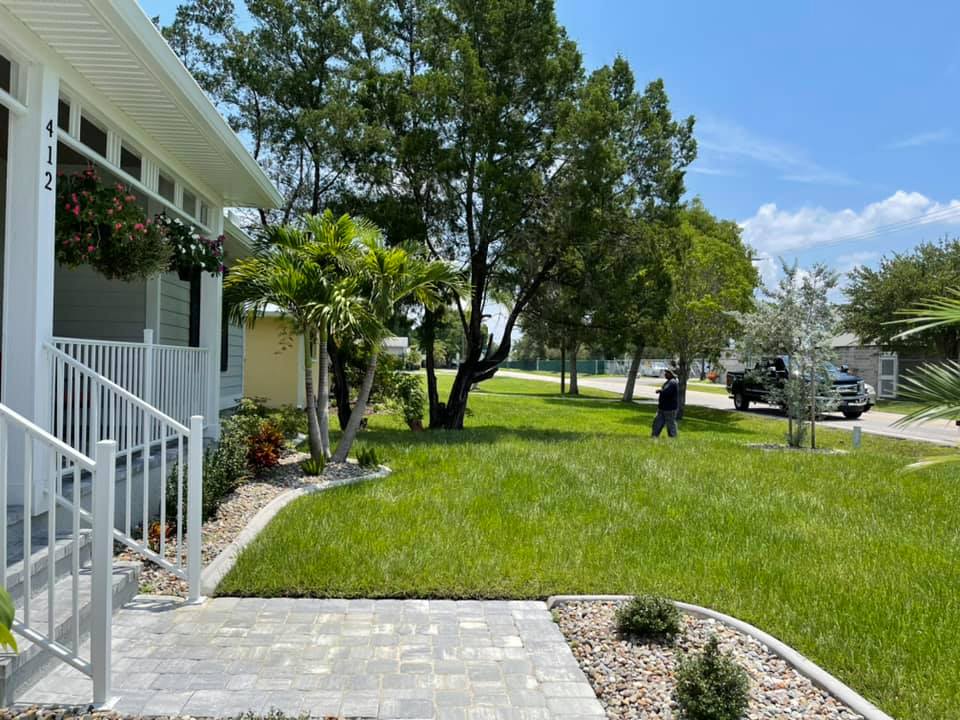 A man is standing in front of a house with a lush green lawn.