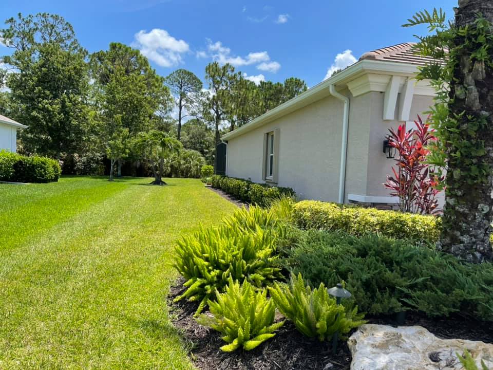 A house with a lush green lawn and bushes in front of it.