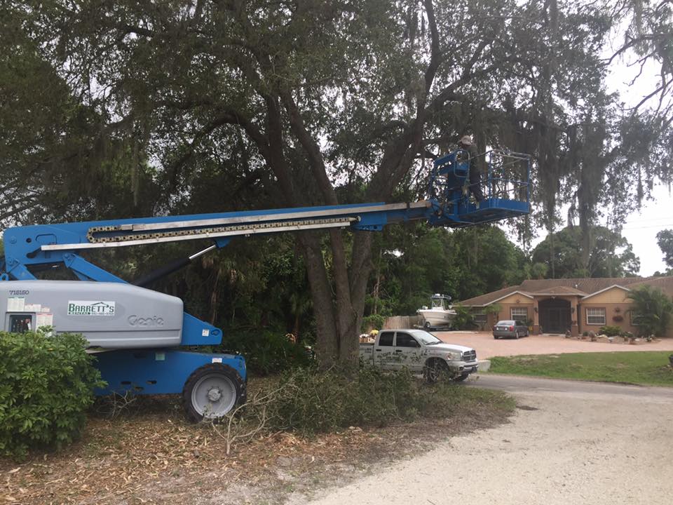 A blue and silver aerial lift is parked in front of a house.