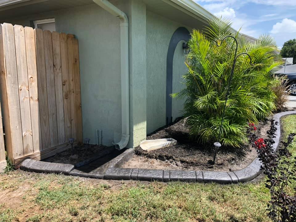 A house with a wooden fence and a garden in front of it.