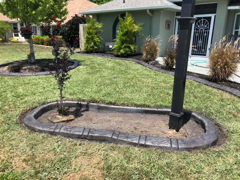 A concrete curb in the middle of a lush green lawn in front of a house.