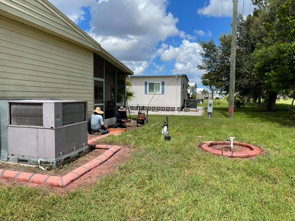 A man is sitting in the grass in front of a mobile home.
