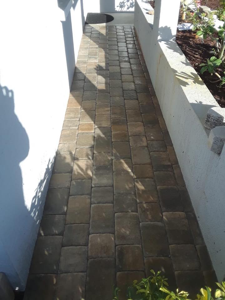 A walkway with bricks on the side of a building