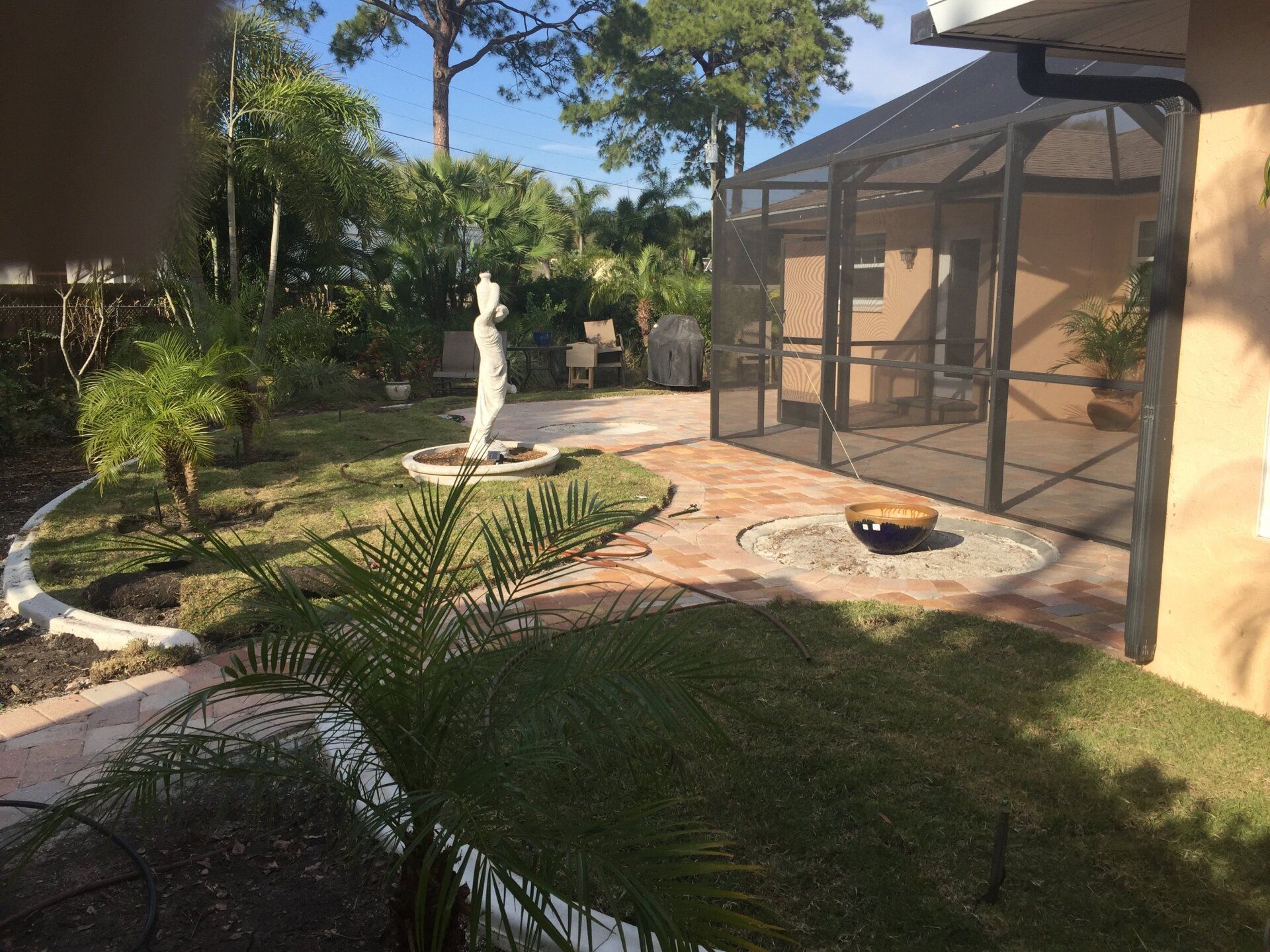 A house with a screened in porch and a statue in the backyard