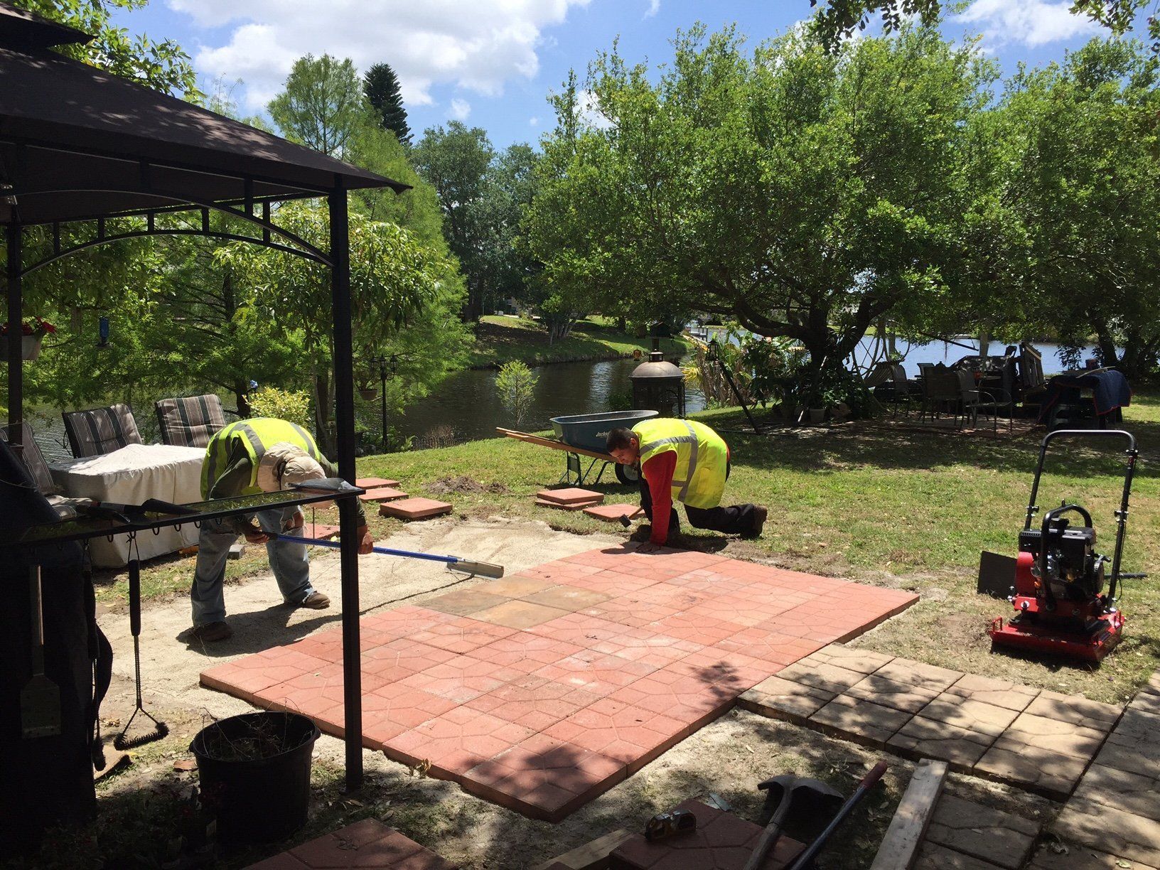 A group of men are working on a patio in a park.