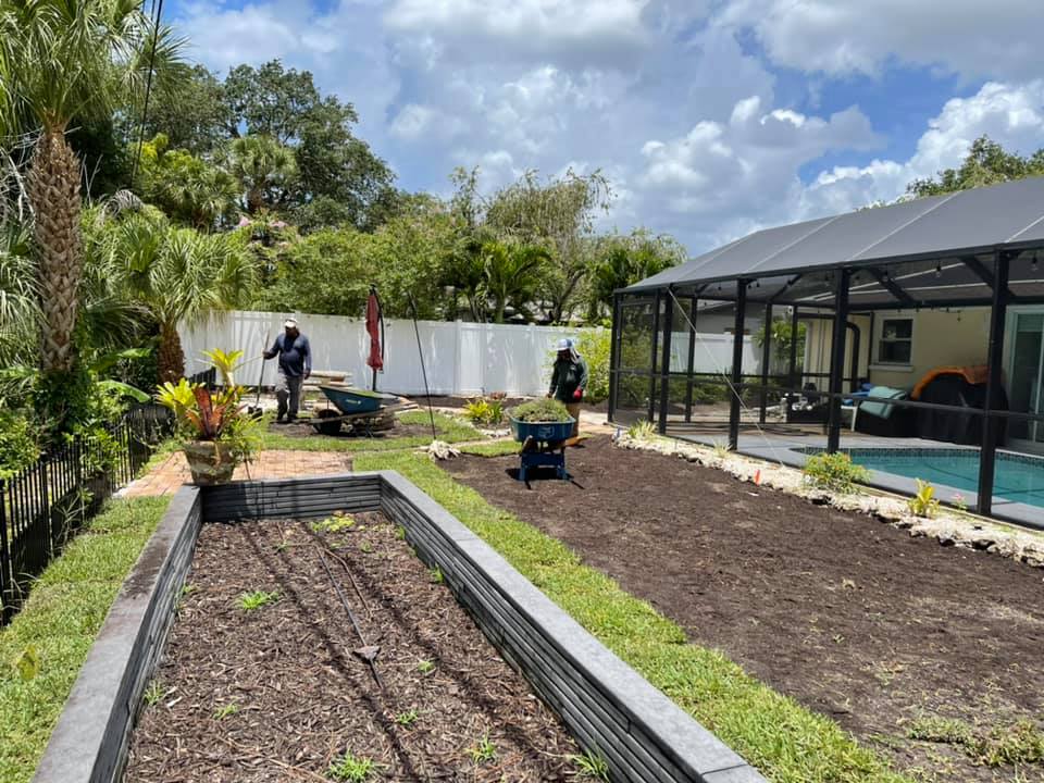 A couple of people are working in a garden in front of a house.