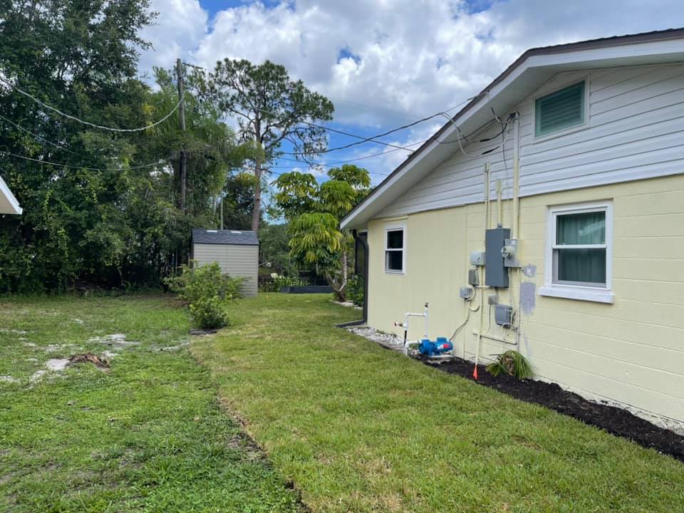 A yellow house with a white siding and a large lawn in front of it.