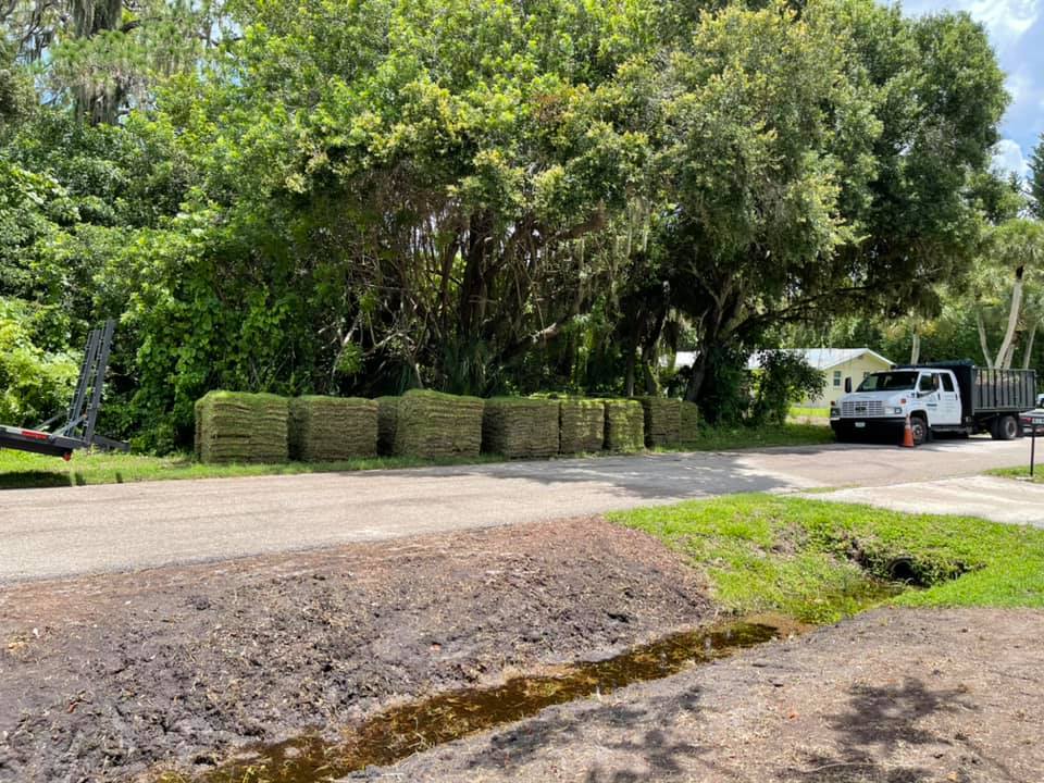 A truck is parked on the side of the road next to a pile of hay.