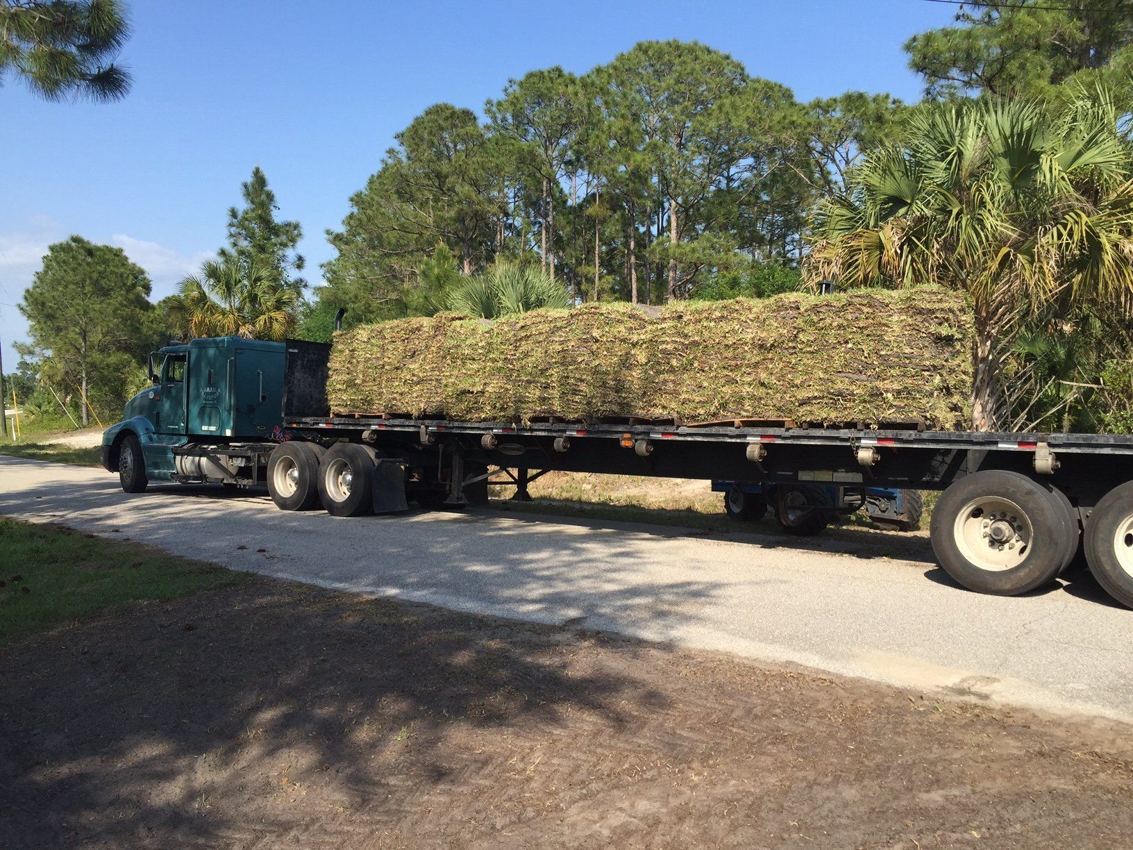 A semi truck is carrying a stack of hay on a trailer.