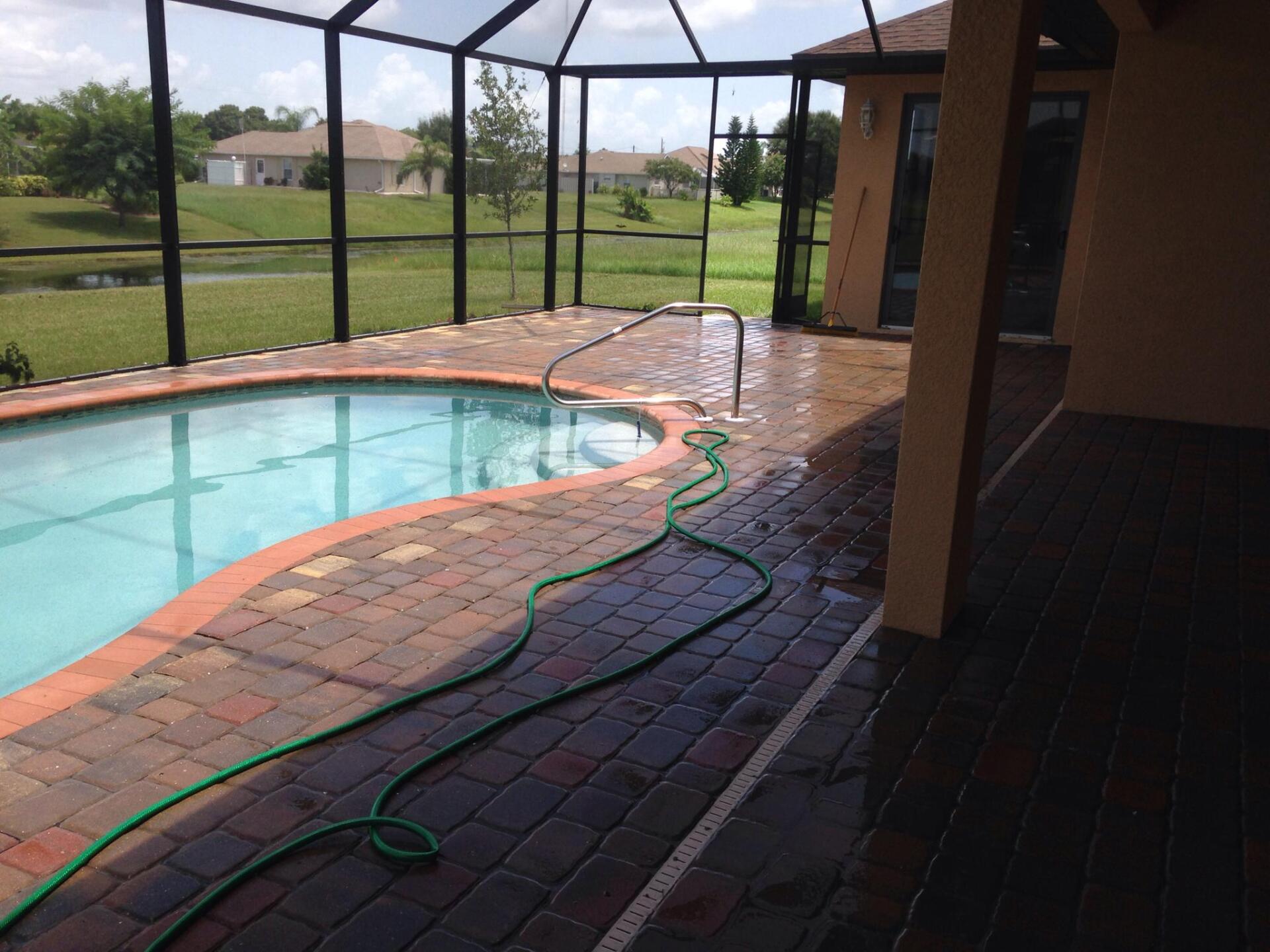 A screened in pool with a green hose attached to it