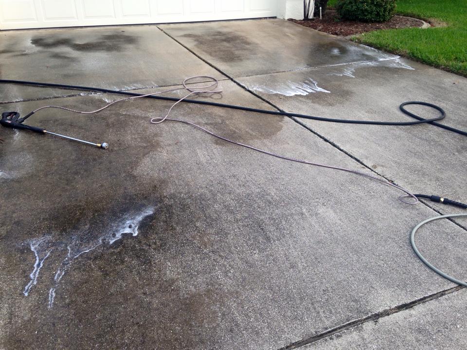 A person is cleaning a driveway with a high pressure washer.
