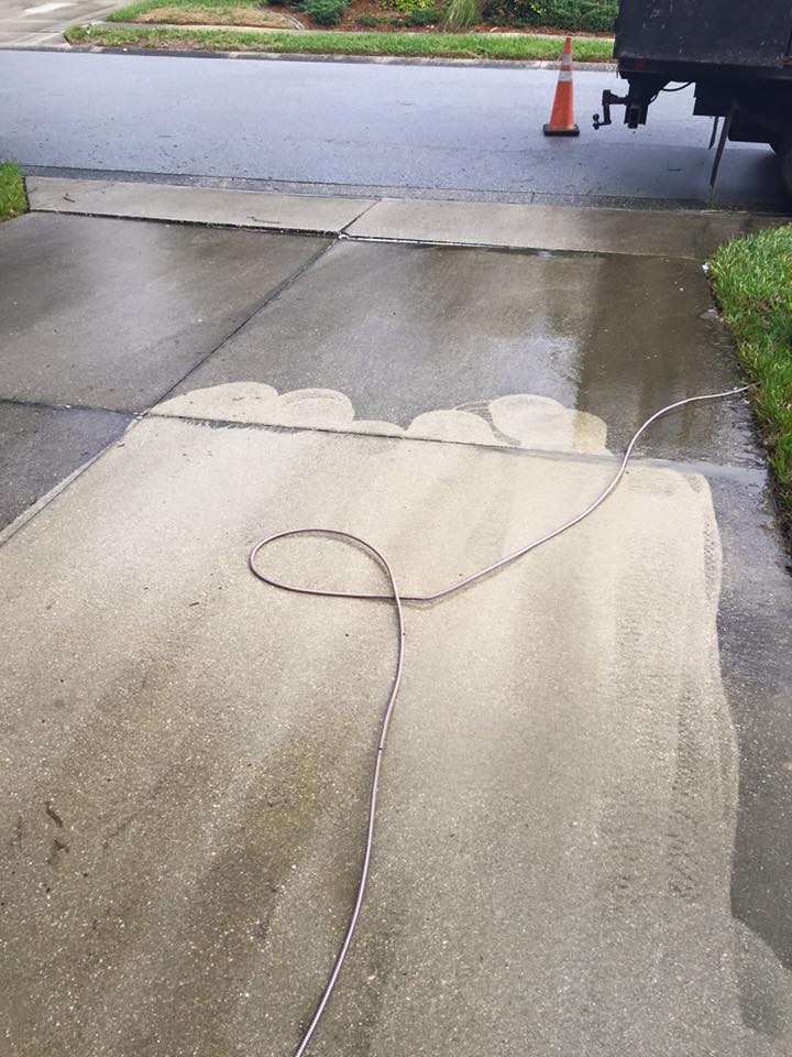 A hose is being used to clean a concrete driveway.