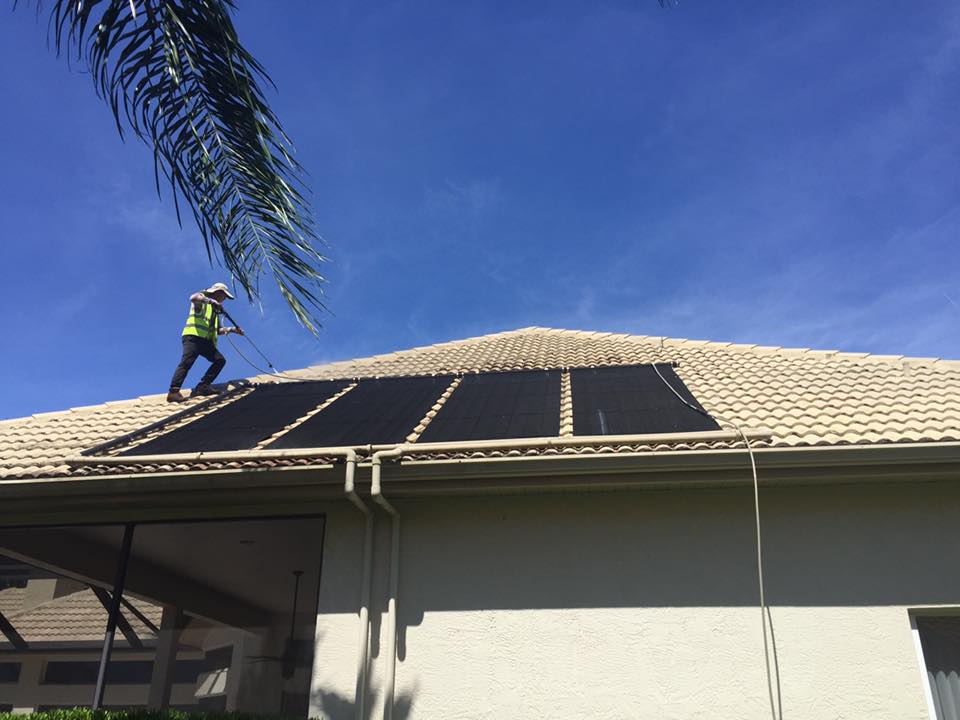 A man is standing on top of a roof with solar panels on it.