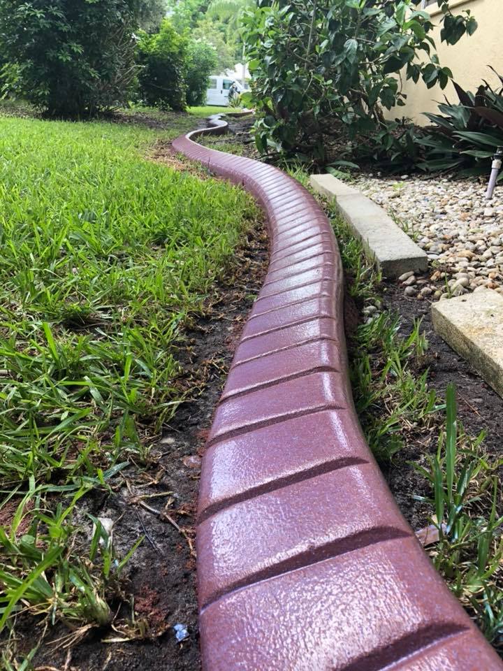 A purple curb is sitting in the middle of a lush green field.