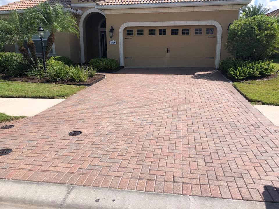 A brick driveway leading to a house with a garage