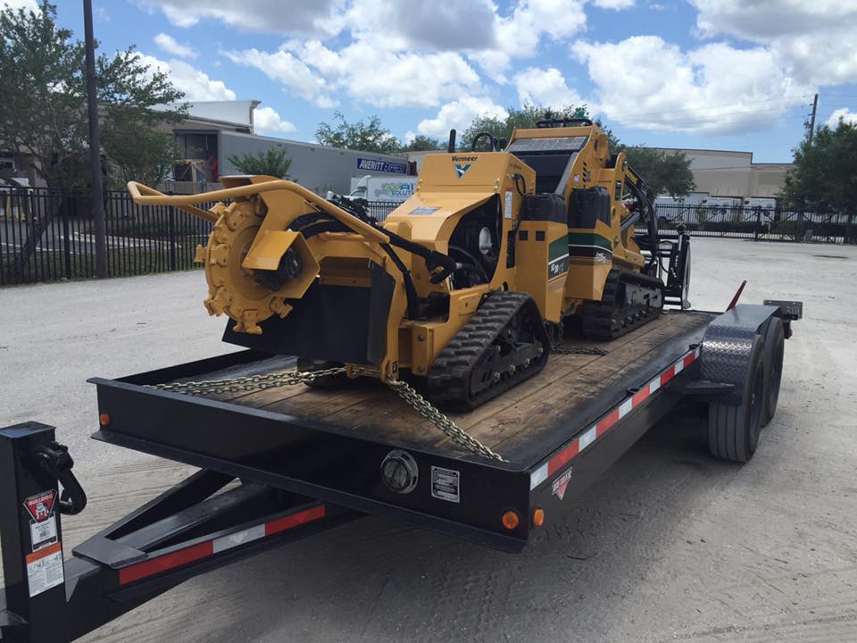 A yellow tractor is sitting on top of a trailer.