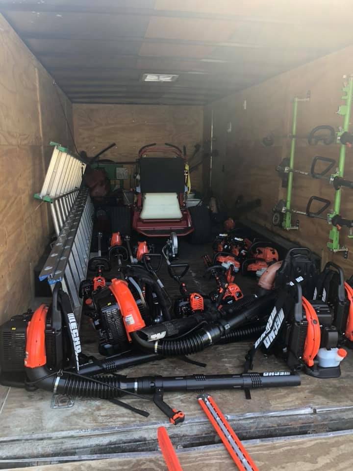 A trailer filled with lots of tools and a lawn mower.