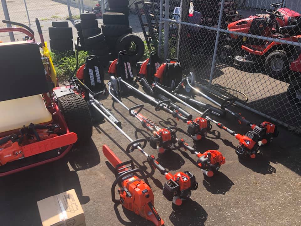 A bunch of lawn mower and trimmers are sitting on the ground