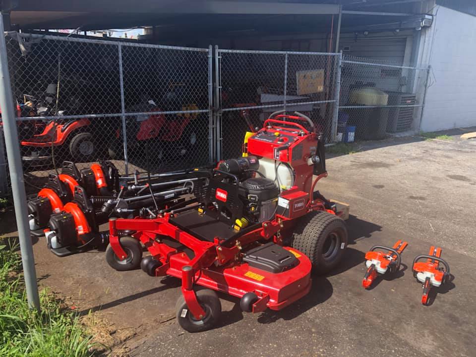 A red lawn mower is parked in front of a chain link fence.