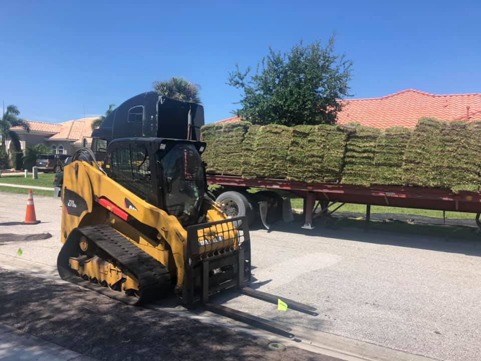 A bulldozer is loading hay onto a trailer.