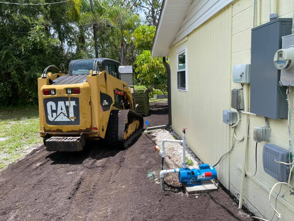 A yellow cat bulldozer is parked in front of a house.