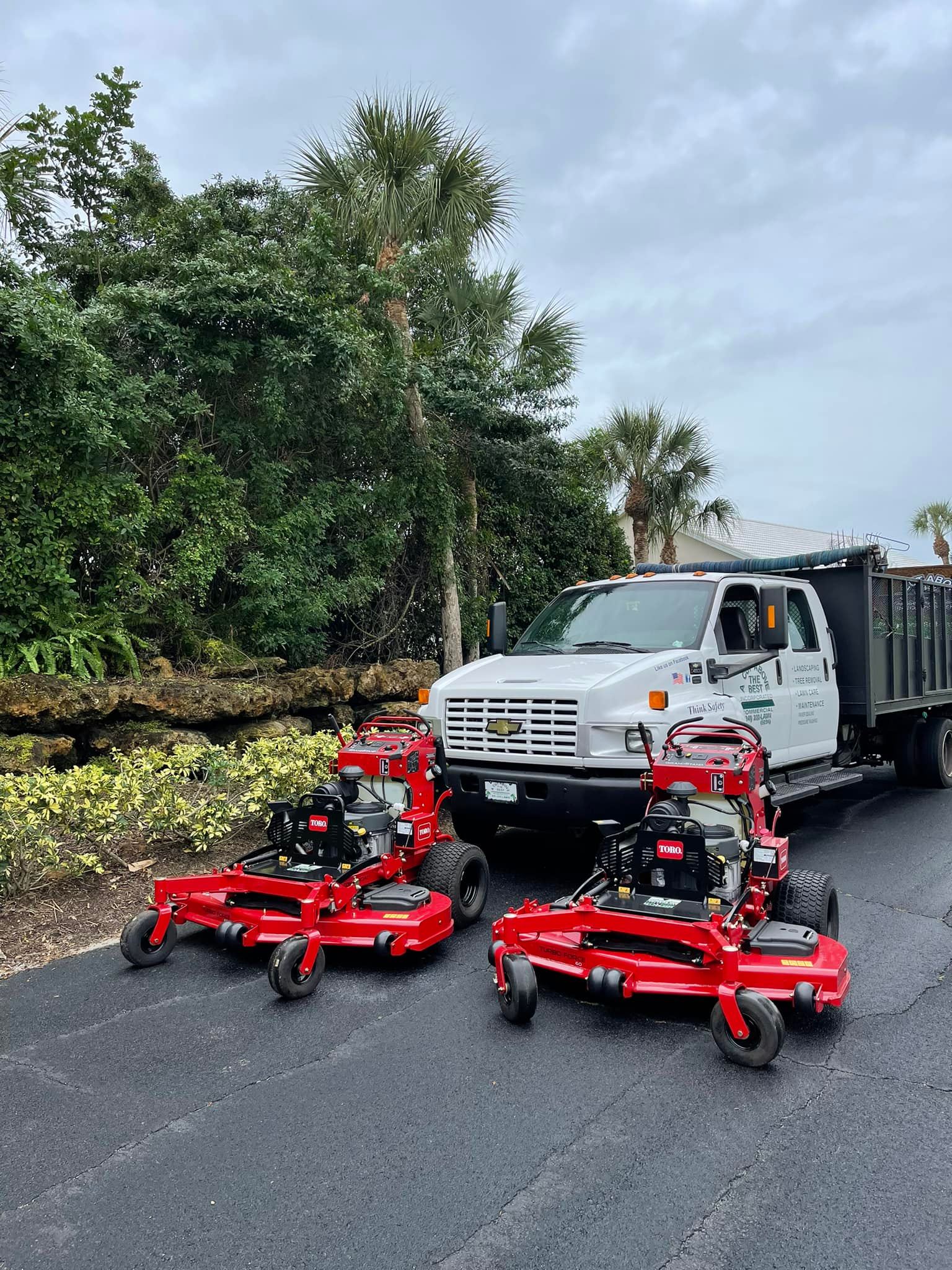 Two lawn mowers are parked next to a truck on the side of the road.