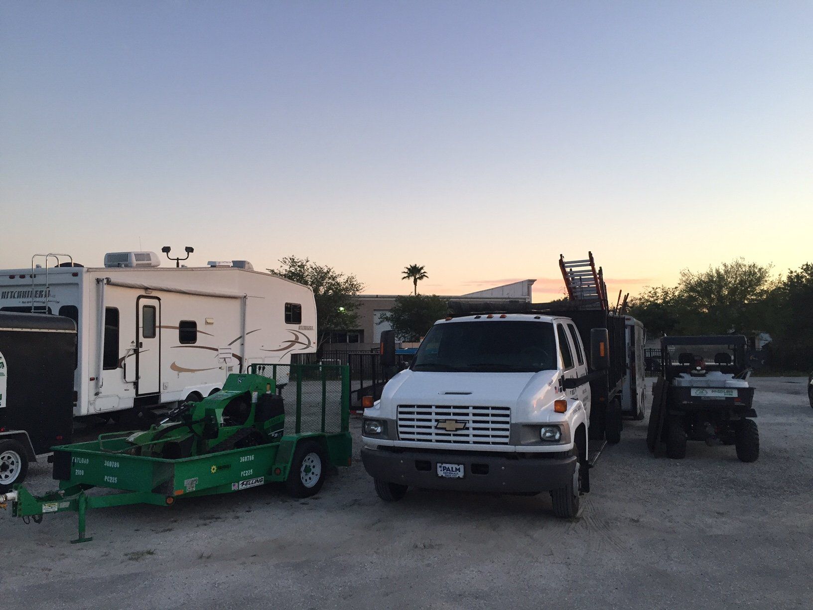 A white truck is parked next to a trailer in a parking lot