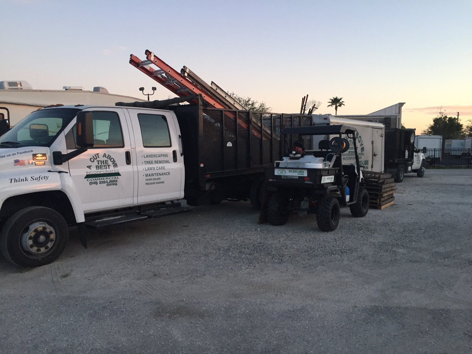 A dump truck with a ladder on top of it is parked next to a utility vehicle.