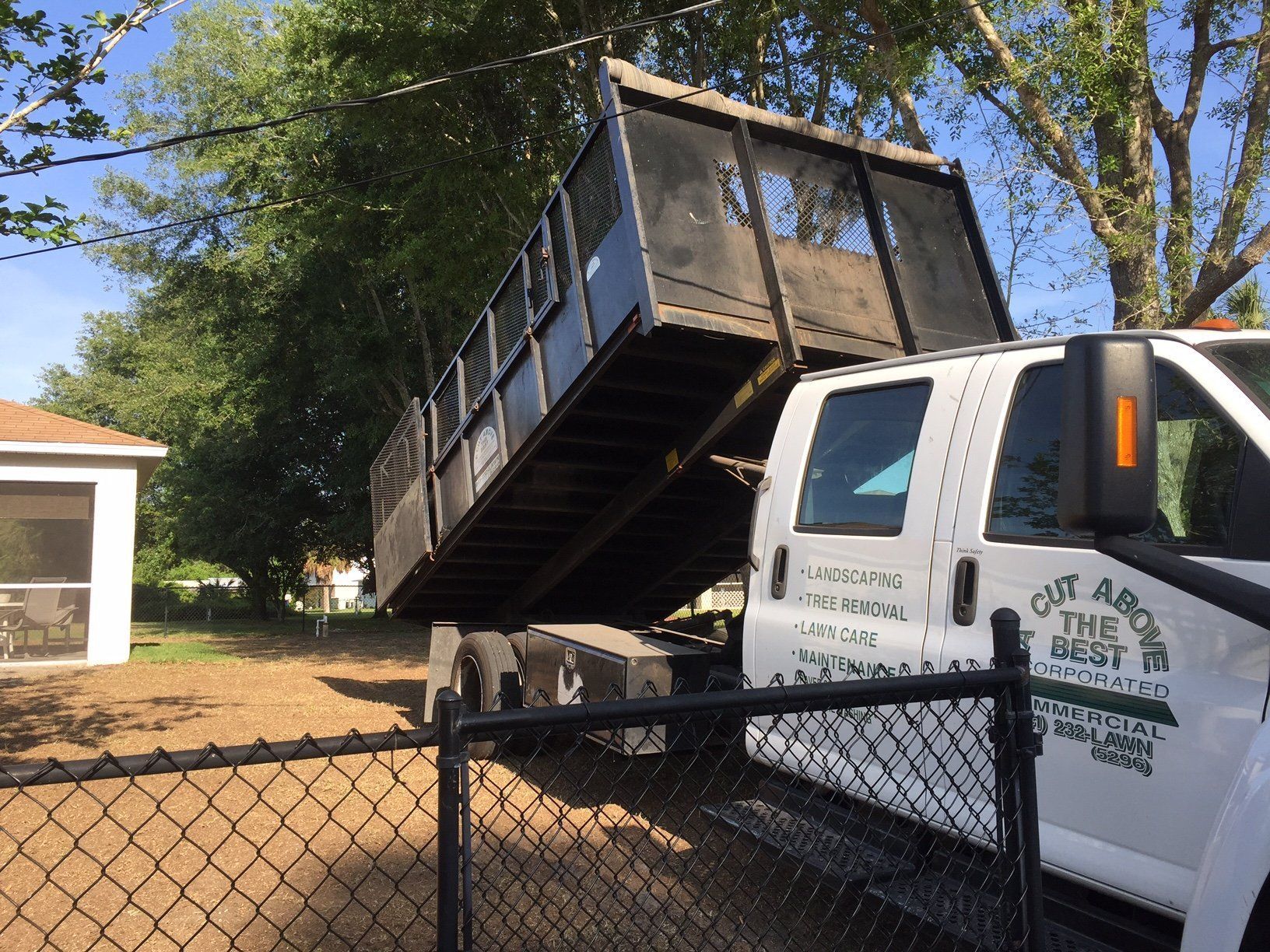 A dump truck is parked in front of a chain link fence.