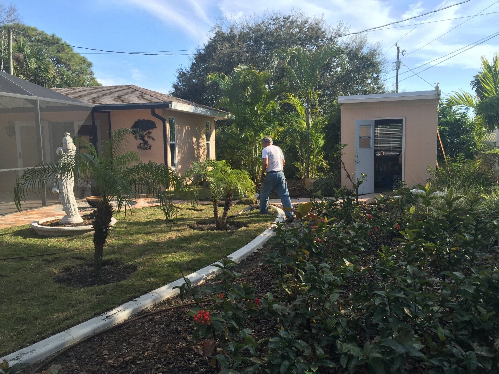 A man is standing in a garden in front of a house