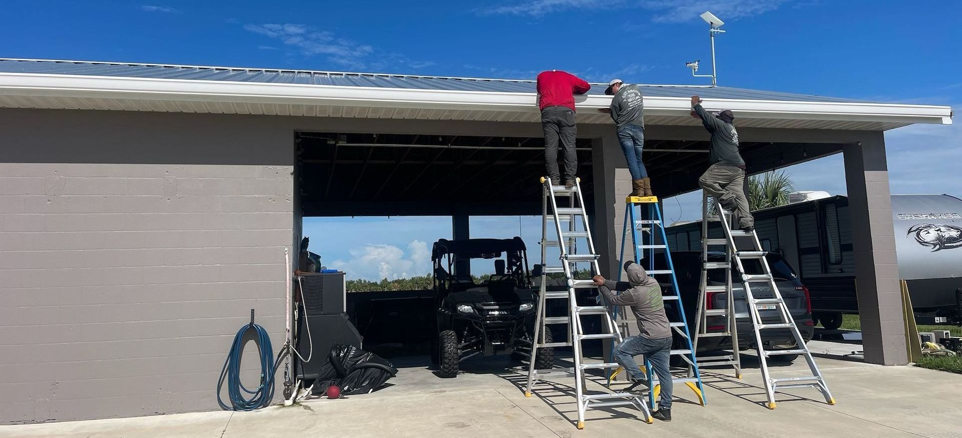 A group of men are working on the roof of a garage.