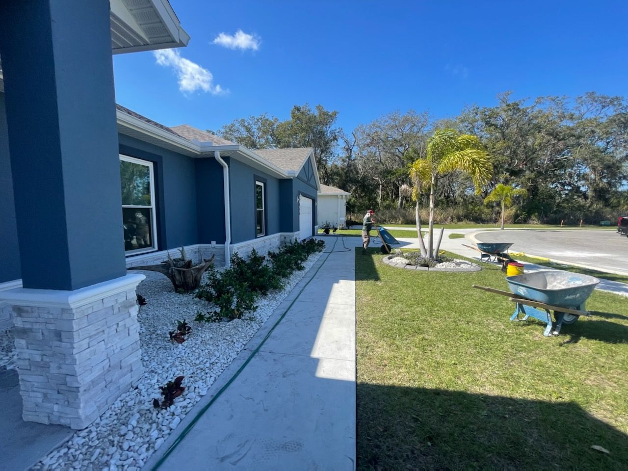A blue house with a wheelbarrow in front of it.