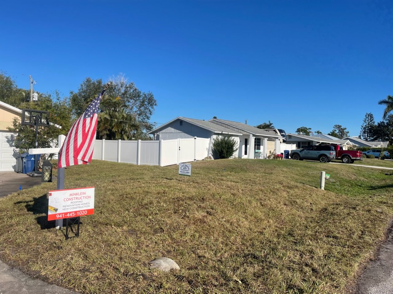 An american flag is flying in the grass in front of a house.