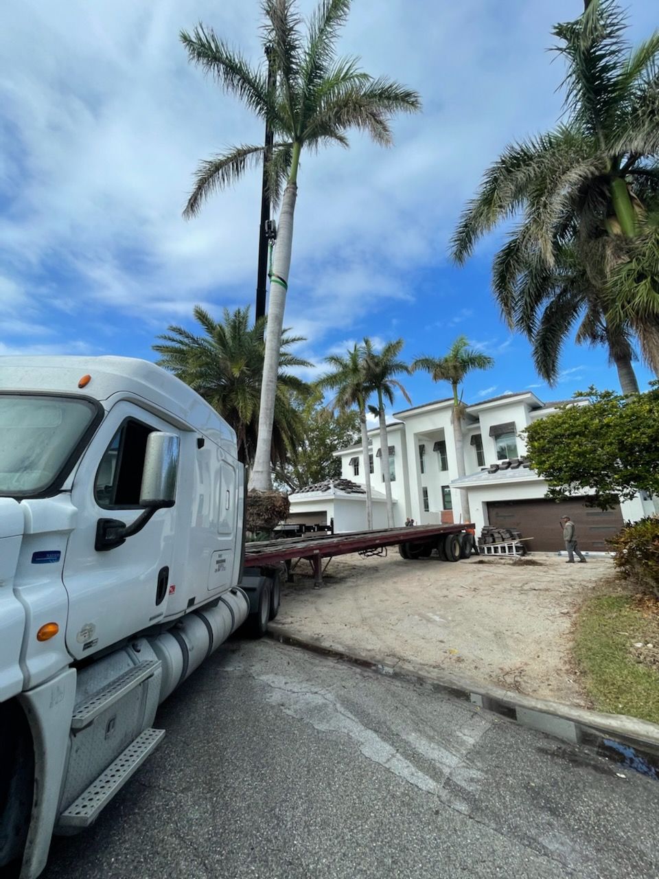 A white truck is parked in front of a large house.